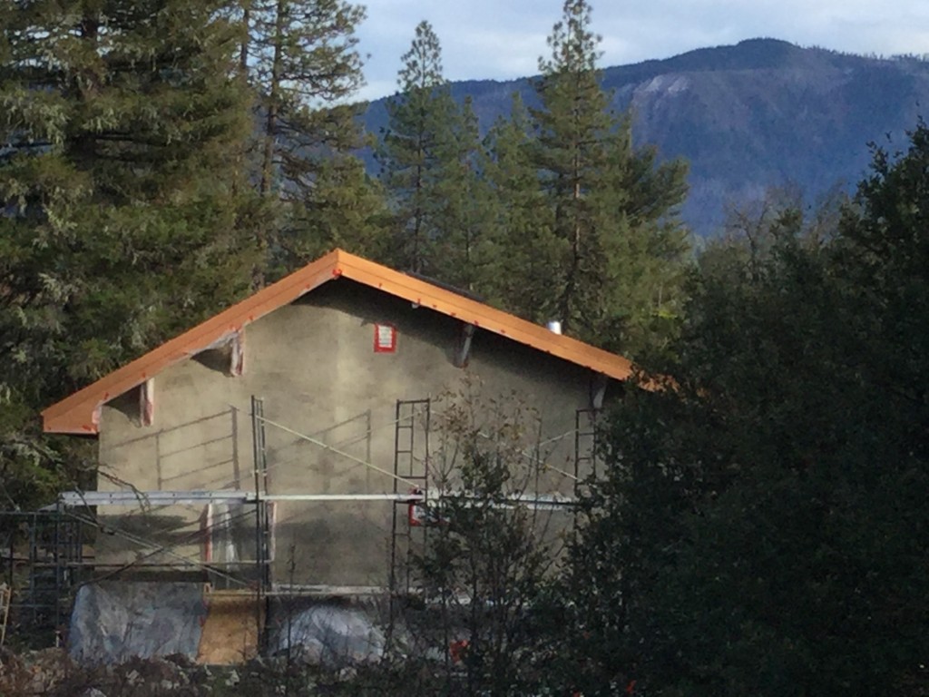 Straw Hall with first coat of Natural Hydraulic Lyme plaster and copper-color steel roof flashing.